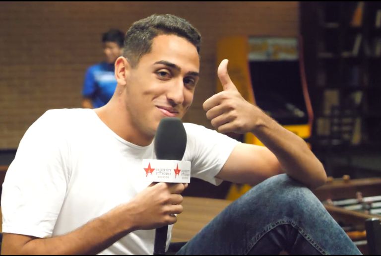Undergraduate student speaking into microphone on the campus of the University of St. Thomas in Houston, Texas