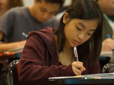 Students writing on paper at their desks in classroom