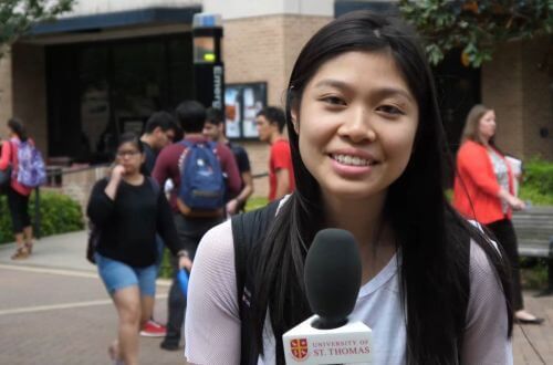 Student holding microphone on campus of University of St. Thomas in Houston, Texas