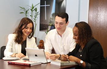 Three University of St. Thomas - Houston business major students work at laptop