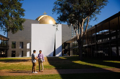 Criminology majors sit on a bench and talk in front of Chapel of St. Basil. on University of St. Thomas - Houston campus