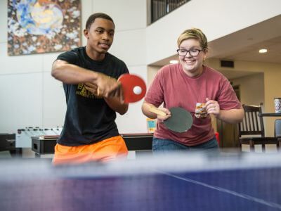 Students playing ping pong inside Guinan Hall dorm at University of St. Thomas in Houston, Texas