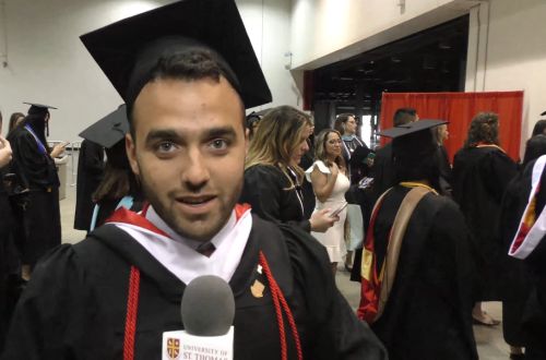 Graduating student holding microphone during commencement pre-ceremony at University of St. Thomas in Houston, Texas