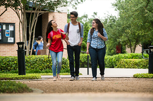 Three students walk on campus at University of St. Thomas in Houston, Texas
